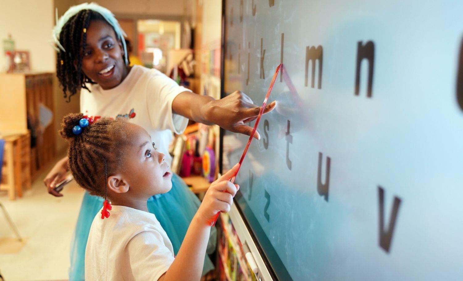 Teacher guiding instruction of student on smartboard