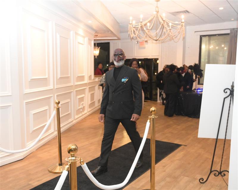 Man wearing masquerade mask on black carpet entrance