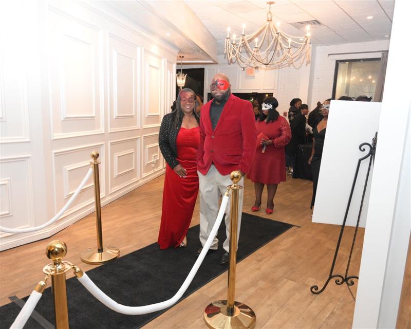 Couple in red wearing masks on black carpet