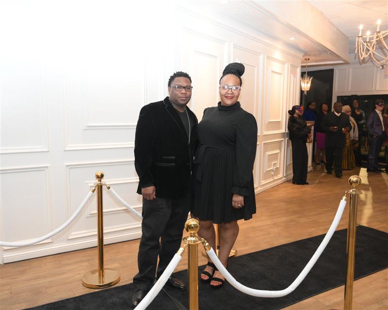 Couple in black smiling on black carpet